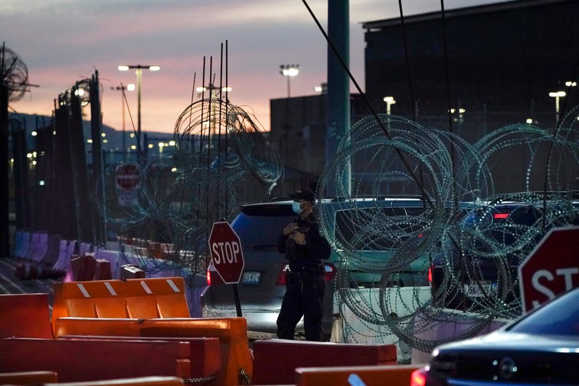 A Customs and Border Protection officer stands at the entrance to the San Ysidro Port of Entry Wednesday, March 2, 2022, seen from Tijuana, Mexico. More than 8,600 Russians have sought refuge in the U.S. on the Mexican border in recent months. To claim asylum in the U.S., they reach a tiny piece of U.S. soil before inspection booths. They must outsmart U.S. officers who try to block their path. (AP Photo/Gregory Bull)