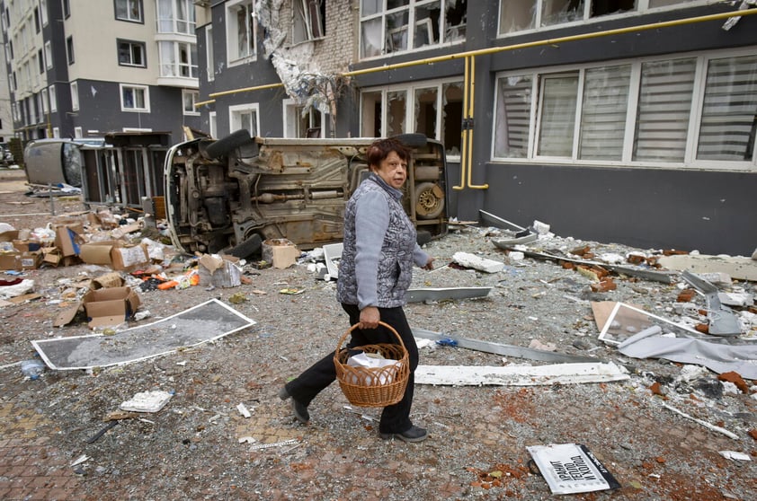 Kyiv (Ukraine), 04/04/2022.- A woman carries food in front of a damaged residential building in Bucha city, which was the recaptured by the Ukrainian army, Kyiv (Kiev) area, Ukraine, 04 April 2022. More than 410 bodies of killed civilians were carried from the recaptured territory in Kyiv's area for exgumation and expert examination. The UN Human Rights Council has decided to launch an investigation into the violations committed after Russia's full-scale invasion of Ukraine as Ukrainian Parliament reported. On 24 February, Russian troops had entered Ukrainian territory in what the Russian president declared a 'special military operation', resulting in fighting and destruction in the country, a huge flow of refugees, and multiple sanctions against Russia. (Rusia, Ucrania) EFE/EPA/OLEG PETRASYUK ATTENTION: GRAPHIC CONTENT