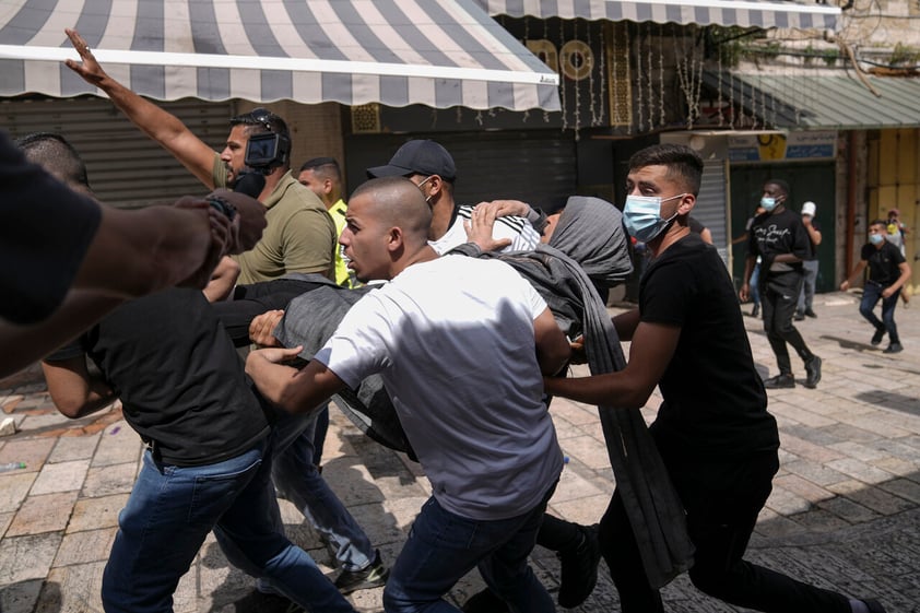 Palestinians carry a woman following clashes between Palestinians and Jews in Jerusalem's Old City as Israelis mark Jerusalem Day, an Israeli holiday celebrating the capture of the Old City during the 1967 Mideast war. Sunday, May 29, 2022. Israel claims all of Jerusalem as its capital. But Palestinians, who seek east Jerusalem as the capital of a future state, see the march as a provocation. Last year, the parade helped trigger an 11-day war between Israel and Gaza militants. (AP Photo/Ariel Schalit)