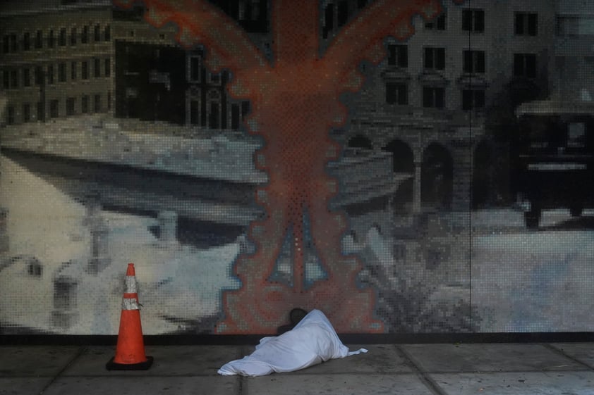 Melvin Lee Hicks, who is homeless, lies under a sheet donated by a nearby hotel, as he shelters alongside a parking garage in downtown Tampa, Fla., during the approach of Hurricane Milton, Wednesday, Oct. 9, 2024. (AP Photo/Rebecca Blackwell)