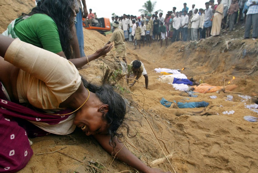 Relatives of victims who were killed by Tsunami waves grieve at the site of a mass burial in Cuddalore, India, Monday, Dec. 27, 2004. (AP Photo/Gurinder Osan, File)