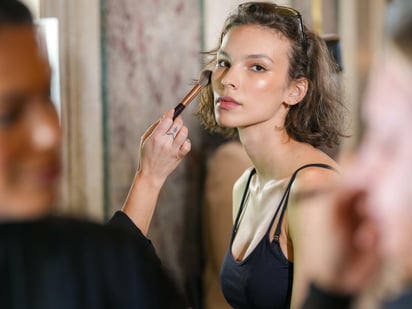 Modelo se prepara usando maquillaje de Charlotte Tilbury para la pasarela de Christian Siriano.  ( EFE/EPA/STEPHANI SPINDEL)