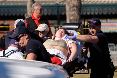 Una persona es atendida de su hombro izquierdo por los paramédicos, en el lugar donde hombres abrieron fuego a la multitud luego de los festejos.