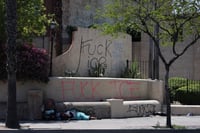 Una persona sin hogar duerme entre grafitis que atacan al Servicio de Inmigración y Control de Aduanas (ICE) durante las protestas provocadas por las redadas migratorias en Los Ángeles, California, el 10 de junio de 2025.