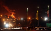 Personas conducen mientras se elevan llamas y humo desde un almacén de petróleo en Teherán, Irán / EFE