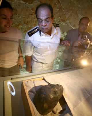 Un policía supervisa la cabeza del faraón niño Tutankamón, envuelta en una sábana de lino, en el momento de su traslado de su sarcófago de oro del Valle de los Reyes, en Egipto. (EFE)