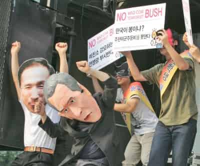 Protestantes sudcoreanos usan mascaras de George W. Bush ay el presidente sudcoreano, Lee Myung-bak, durante las manifestaciones en contra de la visita de Bush a Seúl. (AP)