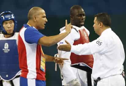 El taekwondista cubano Angel Valodia Matos (c) y su entrenador (iz) discuten con el árbitro,el sueco Chakir Chelbat, momentos antes de que Valodia le diese una patada tras ser descalificado en la pelea por el bronce, categoría de 80 kilos, con el kazajo Arman Chilmanov, que fue declarado vencedor. EFE