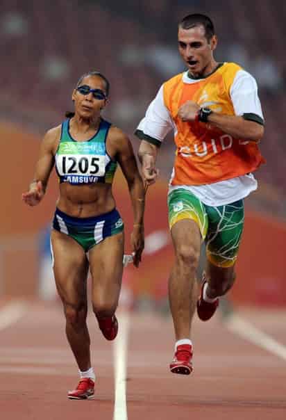 La atleta brasileña Adria Santos tiene como guía a su esposo, con quien obtuvo el oro en la prueba de los 100 metros categoría T11. (AP)