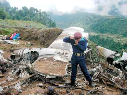 Un policía fotografía los restos de un avión de Yeti Airlines que se estrelló cerca del aeropuerto de la remota localidad de Lukla, en Nepal. (EFE)
