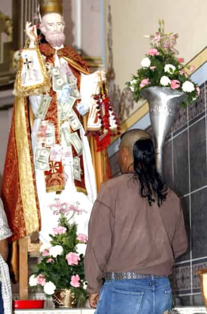 En el templo de San Pedro Apóstol, las imágenes religiosas se encuentran cubiertas de dólares que dejan los migrantes para agradecer que tuvieron trabajo en Estados Unidos. (Agencia Reforma)