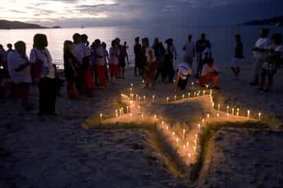 Turistas y nativos encienden velas durante los servicios de remembranza en el Parque del Delfín en la playa de Patong, en Phuket, Tailandia en el cuarto aniversario del tsunami. (AP)