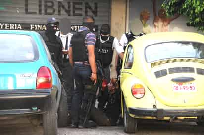 Detenido. Agentes de la Policía Estatal detienen a uno de los asaltantes que quedó herido sobre la acera.