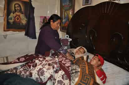 Frío. La señora Olga Moreno de Esparza cobija a sus nietos para que no tengan frío. Su casa es de cartón y madera, pero el aire se cuela por todos los agujeros.