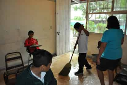 LLuvia. Los alumnos se pusieron a barrer el agua que logró colarse hasta su salón; el problema aparece por ligeras que sean las lluvias.