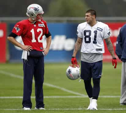 El mariscal de campo de los Patriotas, Tom Brady, dialoga con el ala cerrada Aarón Hernández en un entrenamiento. (AP)