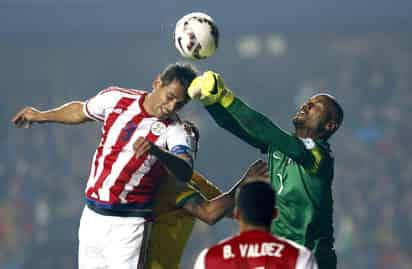 El portero brasileño Jefferson (d) despeja el balón por encima del defensa paraguayo Marcos Antonio Cáceres durante el partido Brasil-Paraguay. (EFE)