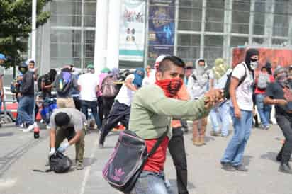 Lucha. Normalistas lanzaron objetos a policías.