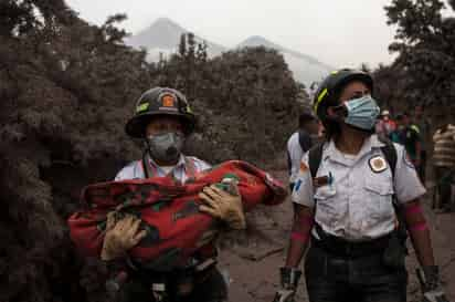 Labor. Una rescatista carga el cuerpo de un menor que falleció en la erupción del volcán. (AP)