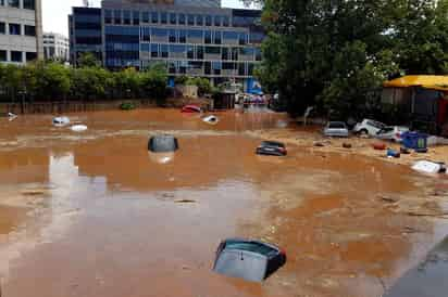 Contraste. Tormenta azota los suburbios del norte de Atenas, mientras rescatistas buscan a desaparecidos por incendios. (EFE)