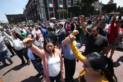 En todo lo alto. Durante el recuerdo por las víctimas del sismo del año pasado, muchos levantaron sus puños en señal de unión. (EL UNIVERSAL)