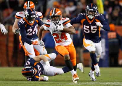 Nick Chubb (c) se escapa de la defensiva de los Broncos.