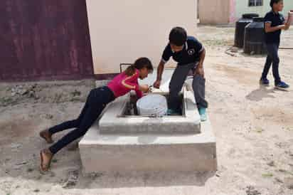 Niños y niñas de la escuela deben llenar los botes de un tinaco enterrado para verter el agua salada en los baños. (EDITH GONZÁLEZ)