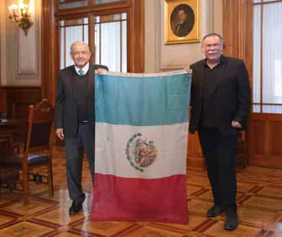 En fotografía. Posan con la bandera de México en la que se ven unas letras escritas bajo el águila, sucia y tocando el piso.