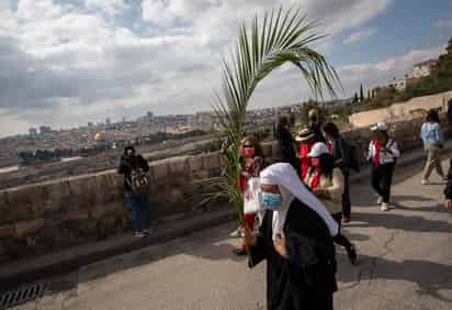 La alegría volvió hoy a la procesión del Domingo de Ramos en Jerusalén, que recrea la entrada triunfal de Jesús desde el Monte de los Olivos, aunque en esta ocasión contó solo con la presencia de locales palestinos y residentes internacionales, debido a la ausencia de peregrinos por la pandemia. (EFE) 
