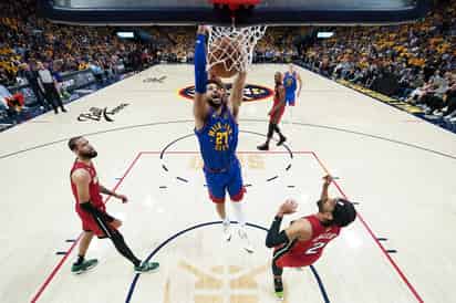 El guardia de Denver, Jamal Murray, clava la pelota en el aro rival sobre la marca de dos jugadores del Miami Heat, durante el primer juego.