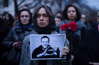 Una mujer sostiene flores y un retrato del destacado opositor ruso Alexei Navalny durante una protesta frente a la embajada rusa en Berlín, Alemania, el viernes 16 de febrero de 2024, tras la noticia de su muerte estando en prisión en Rusia. (Foto AP/Markus Schreiber)

