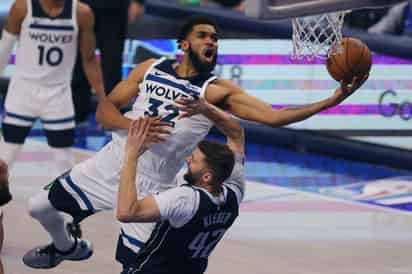 El pívot de los Minnesota Timberwolves, Karl-Anthony Towns (32), conduce hacia la canasta sobre el delantero de los Dallas Mavericks, Maxi Kleber.