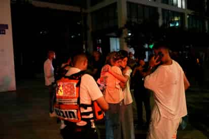 Varias personas aguardan y se apoyan mutuamente junto a un edificio alcanzado por un misil disparado desde Irán, el viernes 13 de junio de 2025, en Tel Aviv, Israel / AP