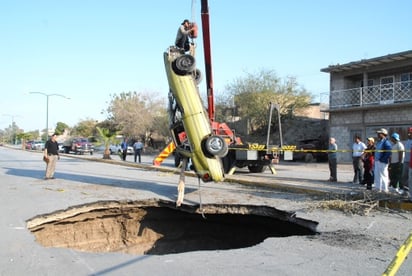 Trabajadores del Municipio sacan un automóvil que cayó a un pozo de cuatro metros de profundidad en el bulevar Río Nazas. Una mujer que iba como pasajero murió por los golpes. La “abra” ocasionada por la avenida del río sólo tiene un pedazo de listón amarillo como señal de precaución y un bordo de tierra que es ignorado. (Fernando Compeán)