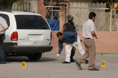 La escena del crimen. Ministeriales recogen los casquillos de bala tras el asesinato de cuatro jóvenes en la colonia Las Alamedas en Torrreón, ayer al mediodía.  EL SIGLO DE TORREÓN