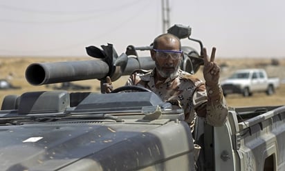 Guerra. Un rebelde libio saluda mientras avanza en un vehículo artillado sobre las carreteras de Ajdabiya.