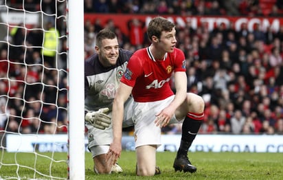 El arquero Mark Bunn (izquierda), del Blackburn Rovers, sonríe luego de atajar una llegada de peligro de William Keane, jugador del Manchester United, durante el partido de ayer en Old Trafford. (AP)