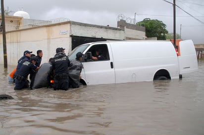 Atorados. Policías empujan una camioneta que cayó en una alcantarilla cuando llevaba personas evacuadas de la Santiago Ramírez.