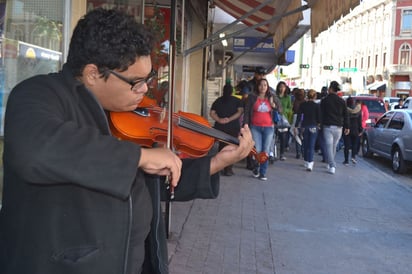 Música. El joven estudiante de violín deleita a los paseantes con música navideña.