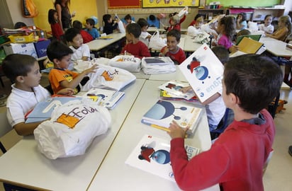 Grupo. Escolares preparan sus libros de texto en un aula de escuela de educación básica.