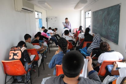 Aula. Aspecto de un aula de clase de nivel medio, donde se observa a una profesora impartiendo su materia. 