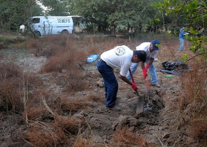 Evidencias. Empleados forenses desentierran cuerpos en una fosa clandestina.