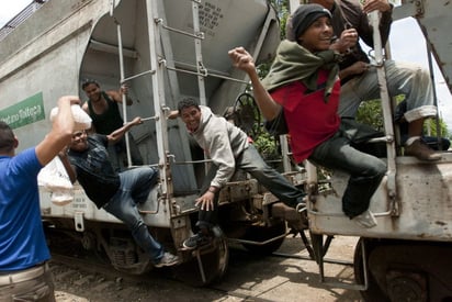 Viaje. Migrantes en el tren 'La Bestia' intentan atrapar una bolsa de comida ofrecida por Las Patronas a su paso por Veracruz. (EFE)