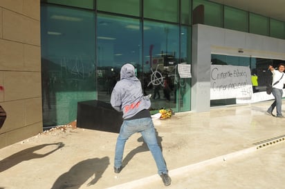 Violencia. Un joven lanza una piedra que quiebra uno de los vidrios de la presidencia. (EL SIGLO DE TORREÓN)