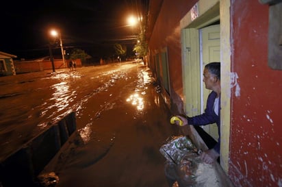 Inundaciones. Una persona se asoma a la puerta tras haber construido una barricada. 