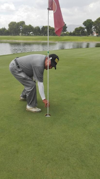 El jugador al momento de sacar su bola dentro del hoyo. Hole in One de Francisco González en La Rosita