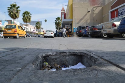 Riesgo de accidente. Sobre una banqueta de la avenida Juárez y calle Blanco hay un registro sin tapa desde hace varios años, vendedores de la zona aseguran que ya ha causado accidentes. (ROBERTO ITURRIAGA)