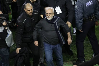 El presidente y propietario del PAOK griego, Ivan Savvidis (centro), abandona el terreno de juego escoltado por sus guardaespaldas.