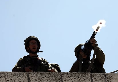 Reacción. Militares israelíes disparan una granada de gas contra manifestantes palestinos, ayer en Hebron.