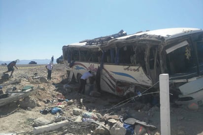 Accidente. Personal de cuerpos de rescate inspecciona el sitio en donde un autobús se volcó la mañana de ayer en la carretera Cuatrociénegas-San Pedro; el saldo de la tragedia es de siete personas muertas, entre ellas cuatro menores de edad, y al menos 20 lesionadas. (CORTESÍA)